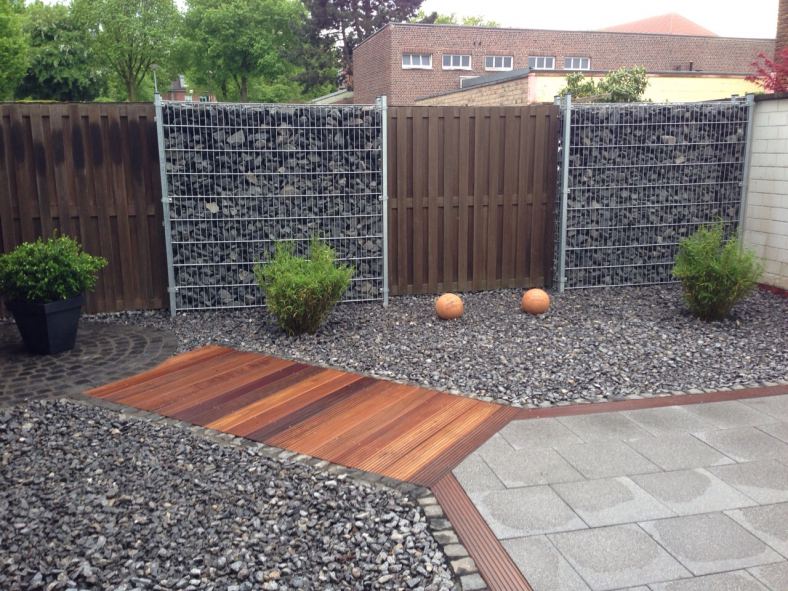 Fertiggestellte Gartenanlage mit Gabionenwänden und Holzterrasse von Gartengestaltung Krahwinkel