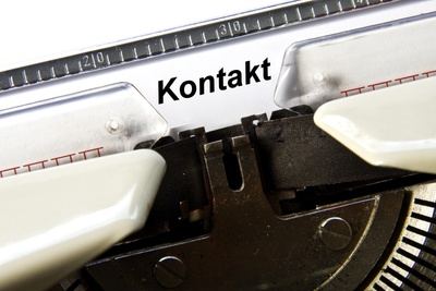 Schreibmaschine mit eingespanntem Blatt und dem Wort Kontakt
